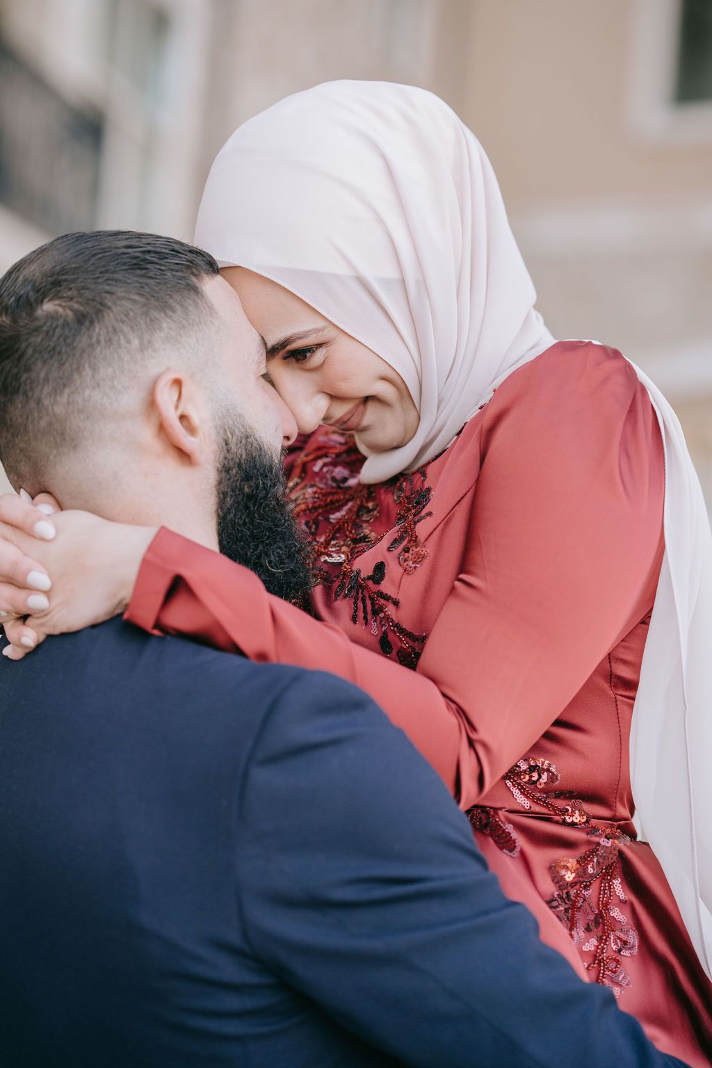 Intimate moment between couple wearing navy suit and red embellished dress.