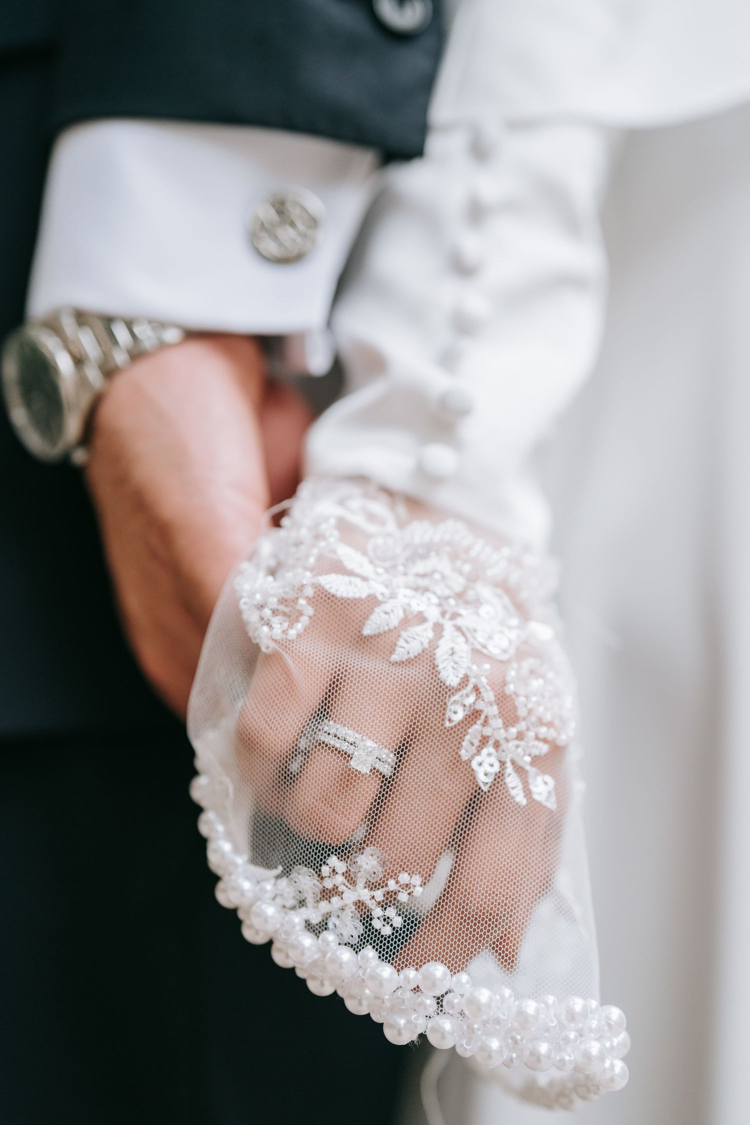 Dallas bride and groom holding hands with attention to their cuffs.
