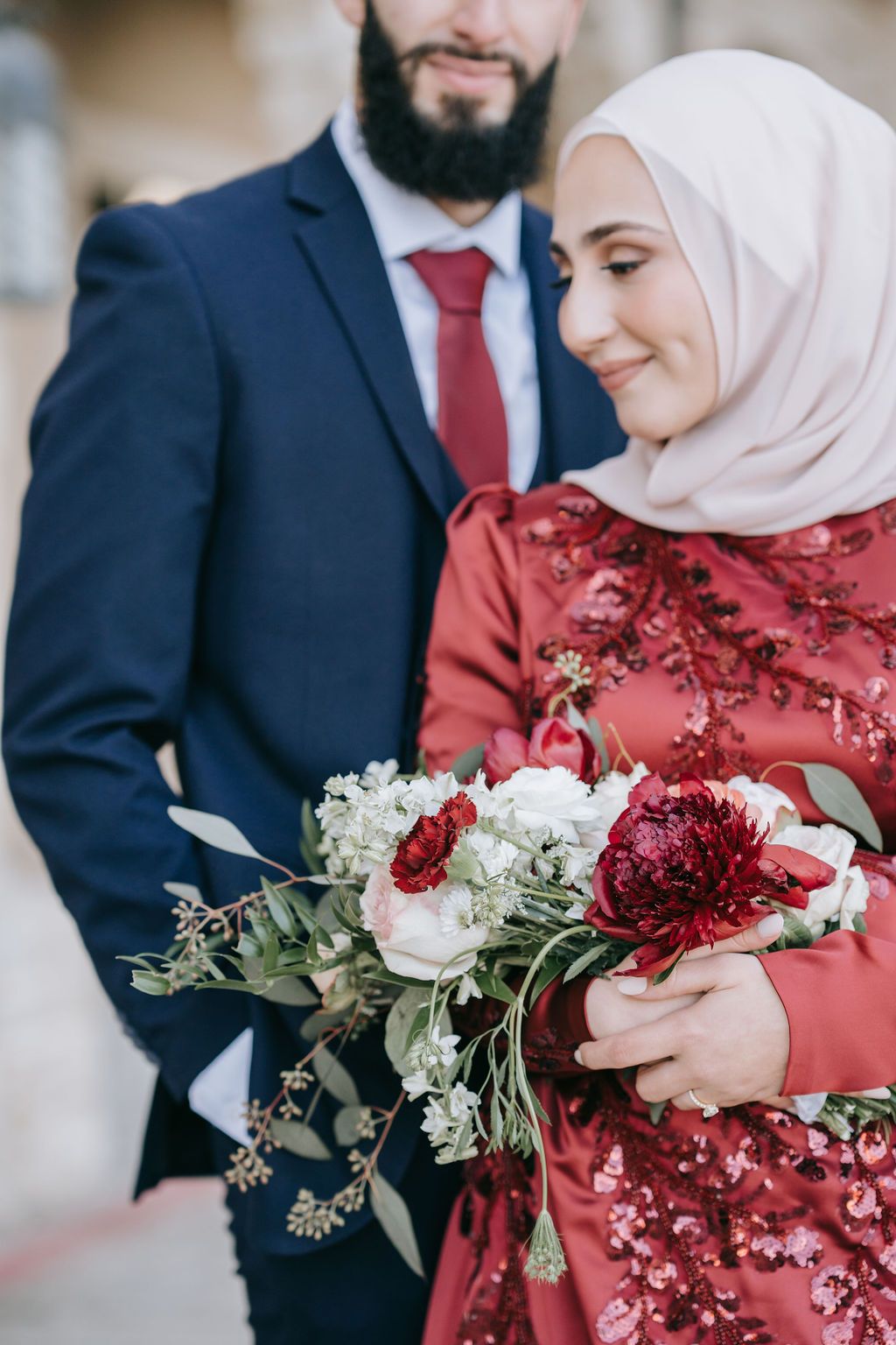 Romantic couple with beautiful red and white floral bouquet in formal wedding attire.