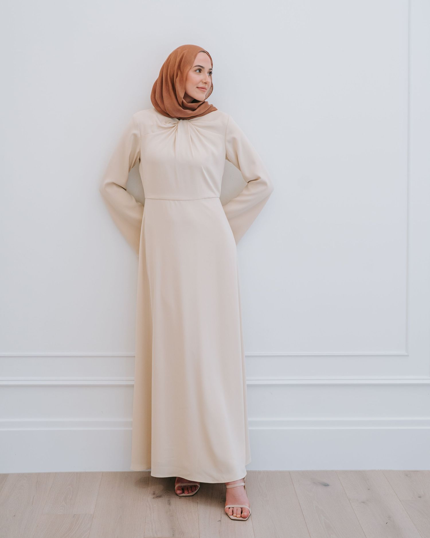Dallas fashion influencer wearing modest beige dress posing indoors for fashion photoshoot in natural light.