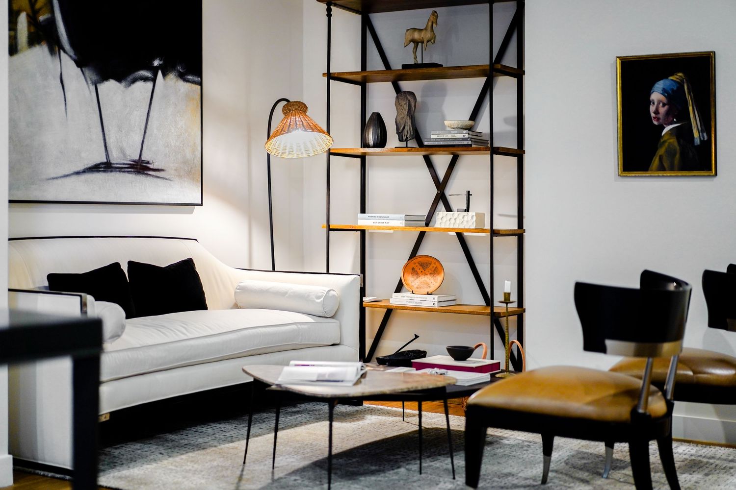 Modern living room with industrial bookshelf, white sofa, and artistic wall decor.