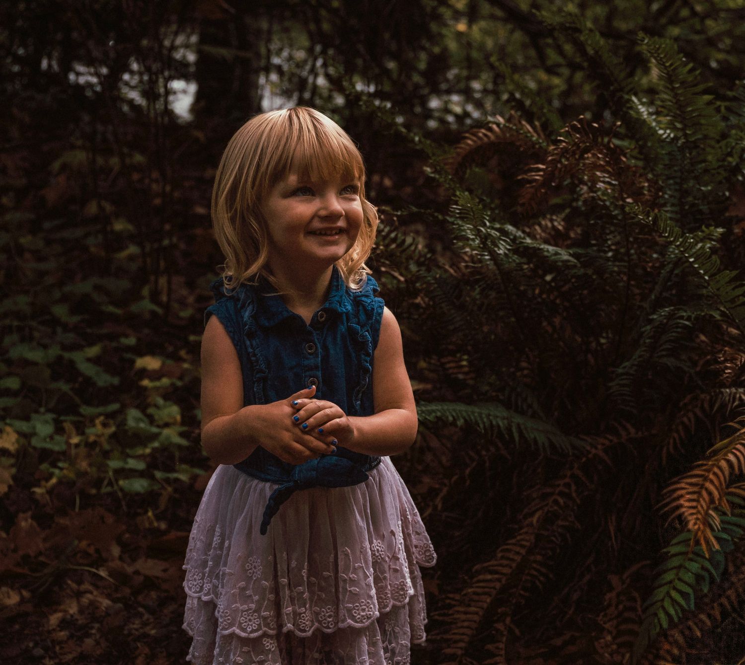 A portrait of a smiling little girl in a forest.