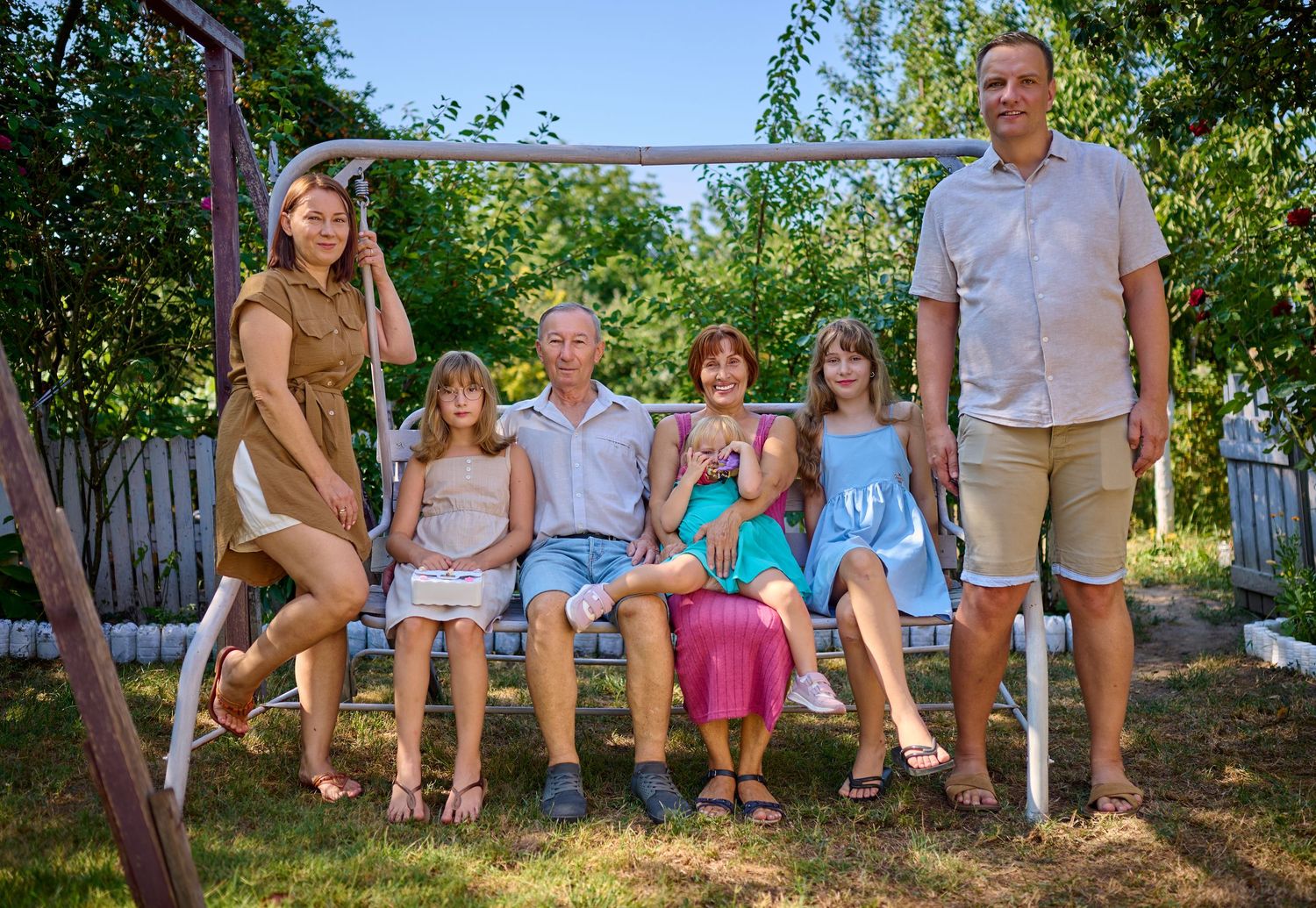 Portret de familie cu trei generații, fotografiate împreună în gradină.