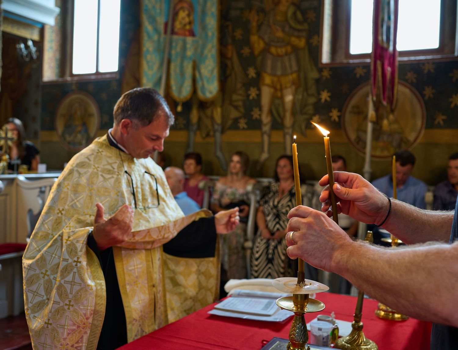 Preot în timpul botezului, fotografiat într-un moment ritualic în biserică.