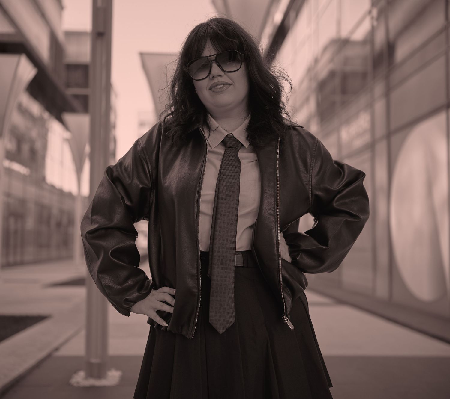 Portret feminin urban, cu ținută dark și atitudine puternică, fotografiat într-un cadru industrial.