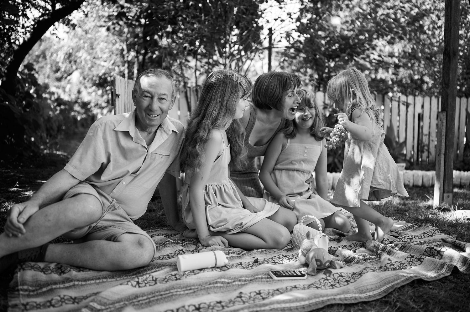 Portret de familie alb-negru cu mai multe generații, fotografiate împreună în grădină.