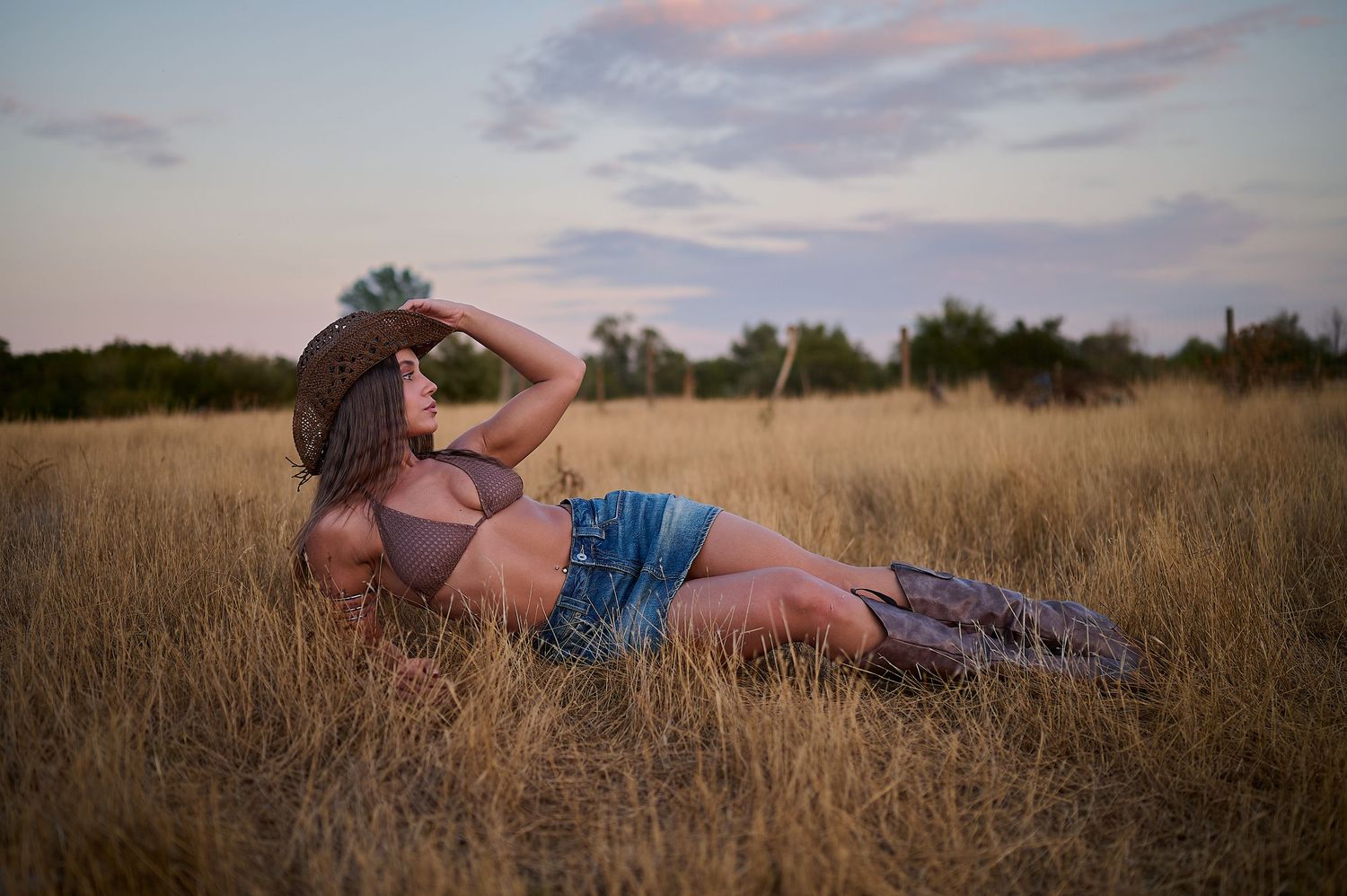 Portret editorial feminin în iarbă, într-un cadru natural cu lumină și umbre puternice.