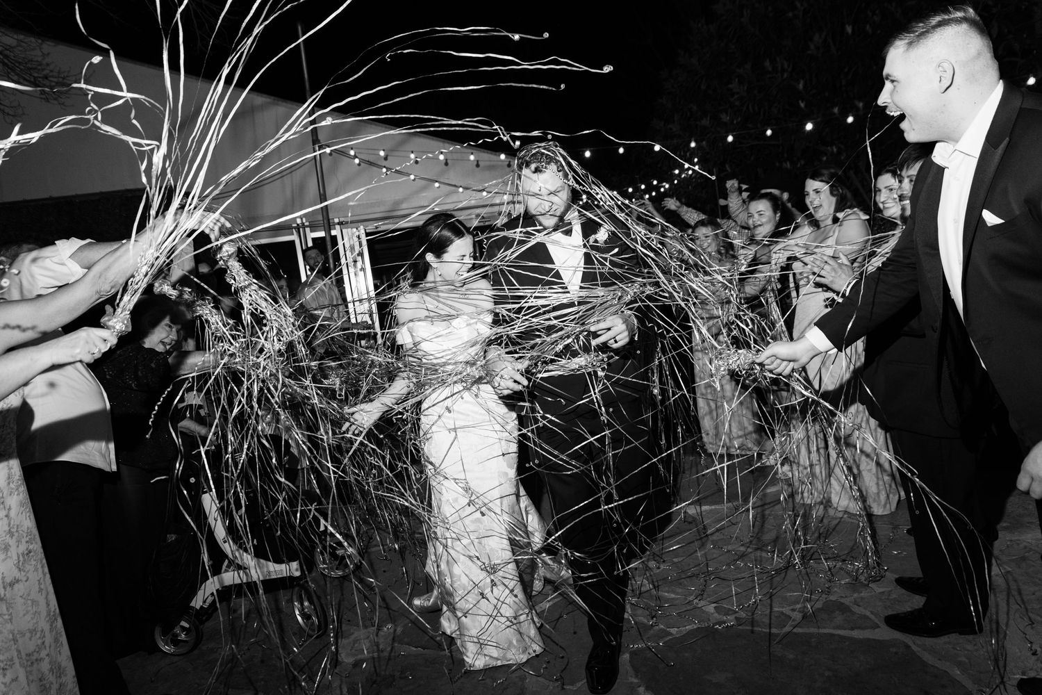 Black and white photo of bride and groom exiting through sparkler send-off celebration.