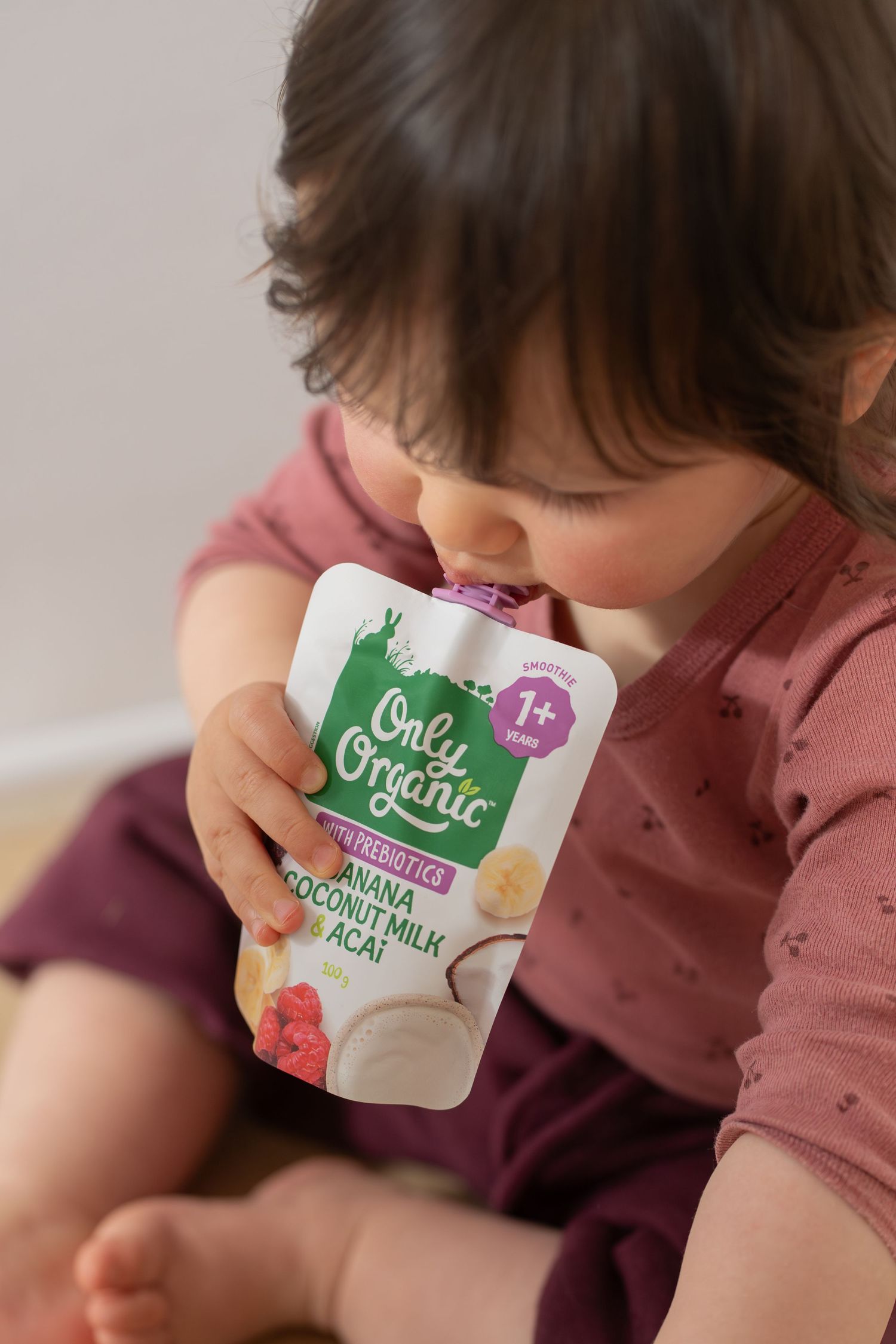 Toddler eating Only Organic prebiotic banana coconut milk acai food pouch, suitable for 1+ years.