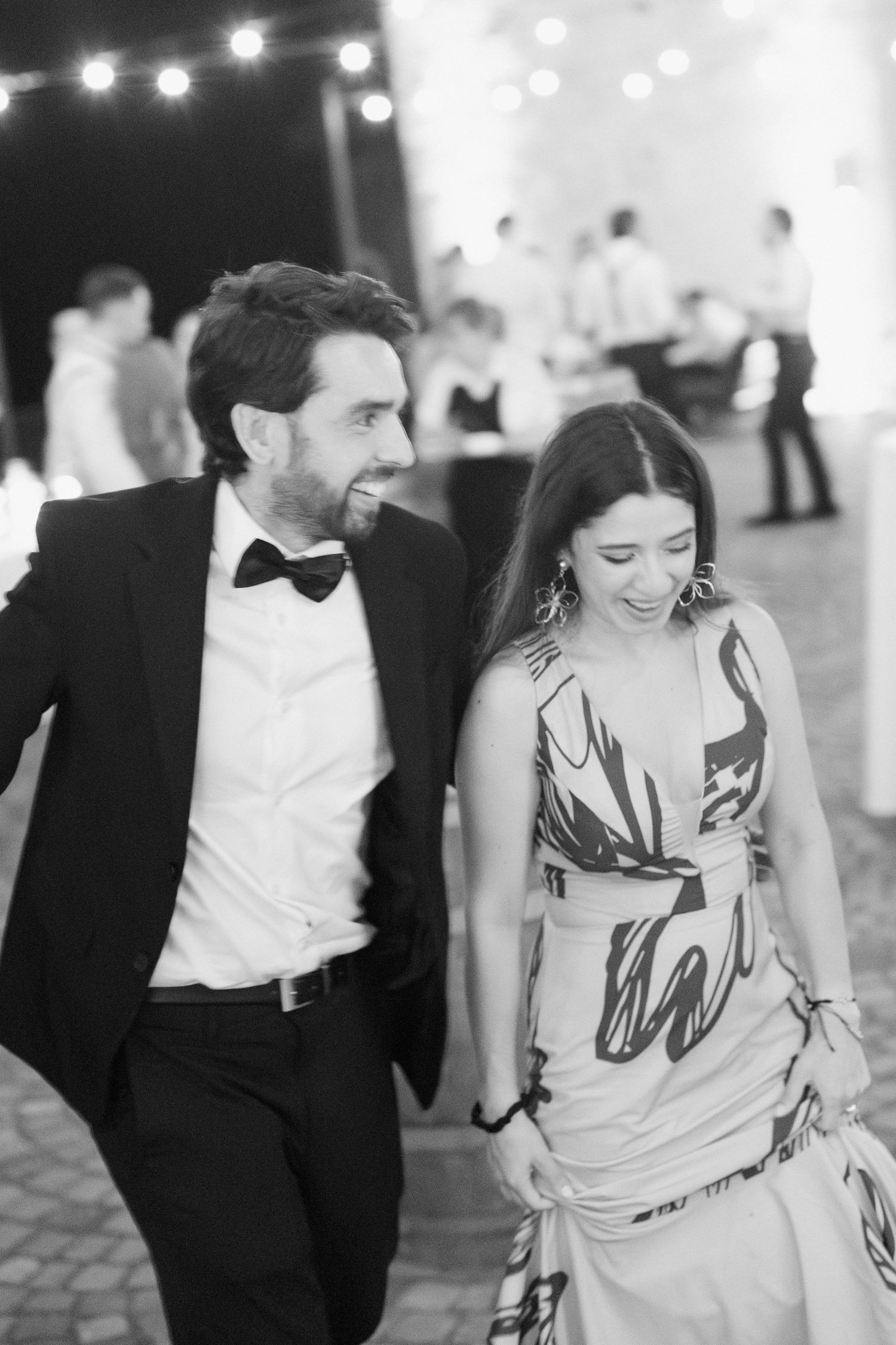 Elegant couple in formal attire share a joyful moment at a wedding reception.