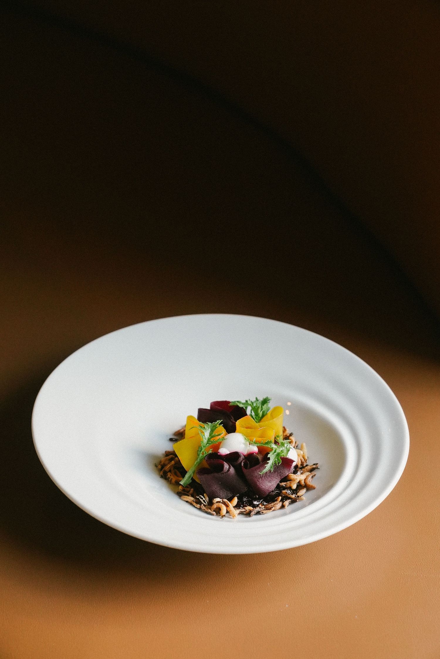 Elegant fine dining beet salad with wild rice, microgreens, and yellow beet on a white plate.