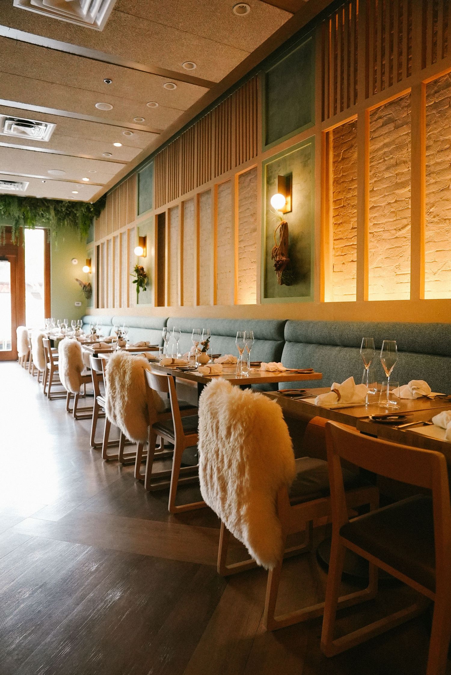 Elegant restaurant dining room with tufted banquette seating, fur chairs, and warm wood paneling.