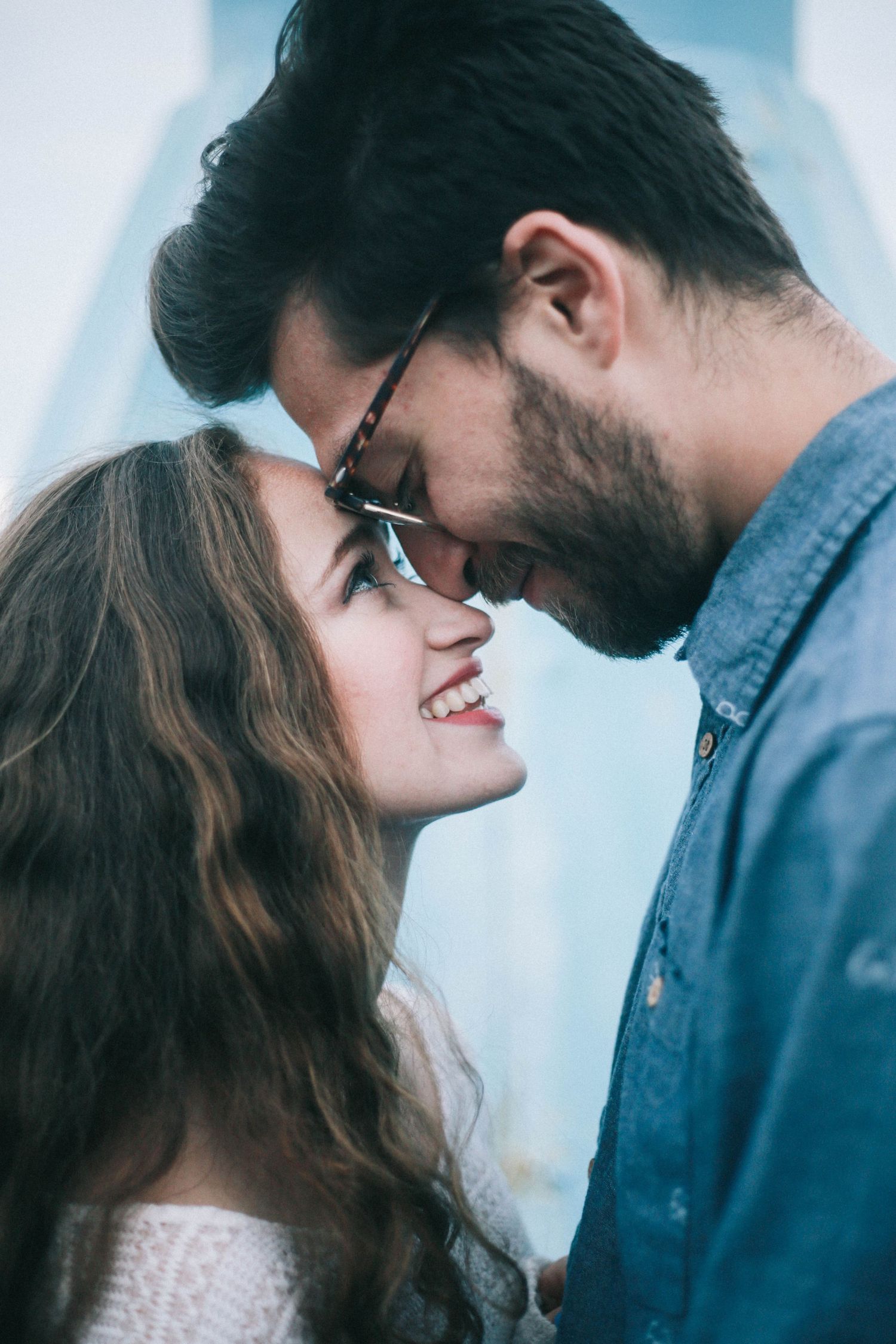 Happy couple touching foreheads and smiling closely together outdoors.