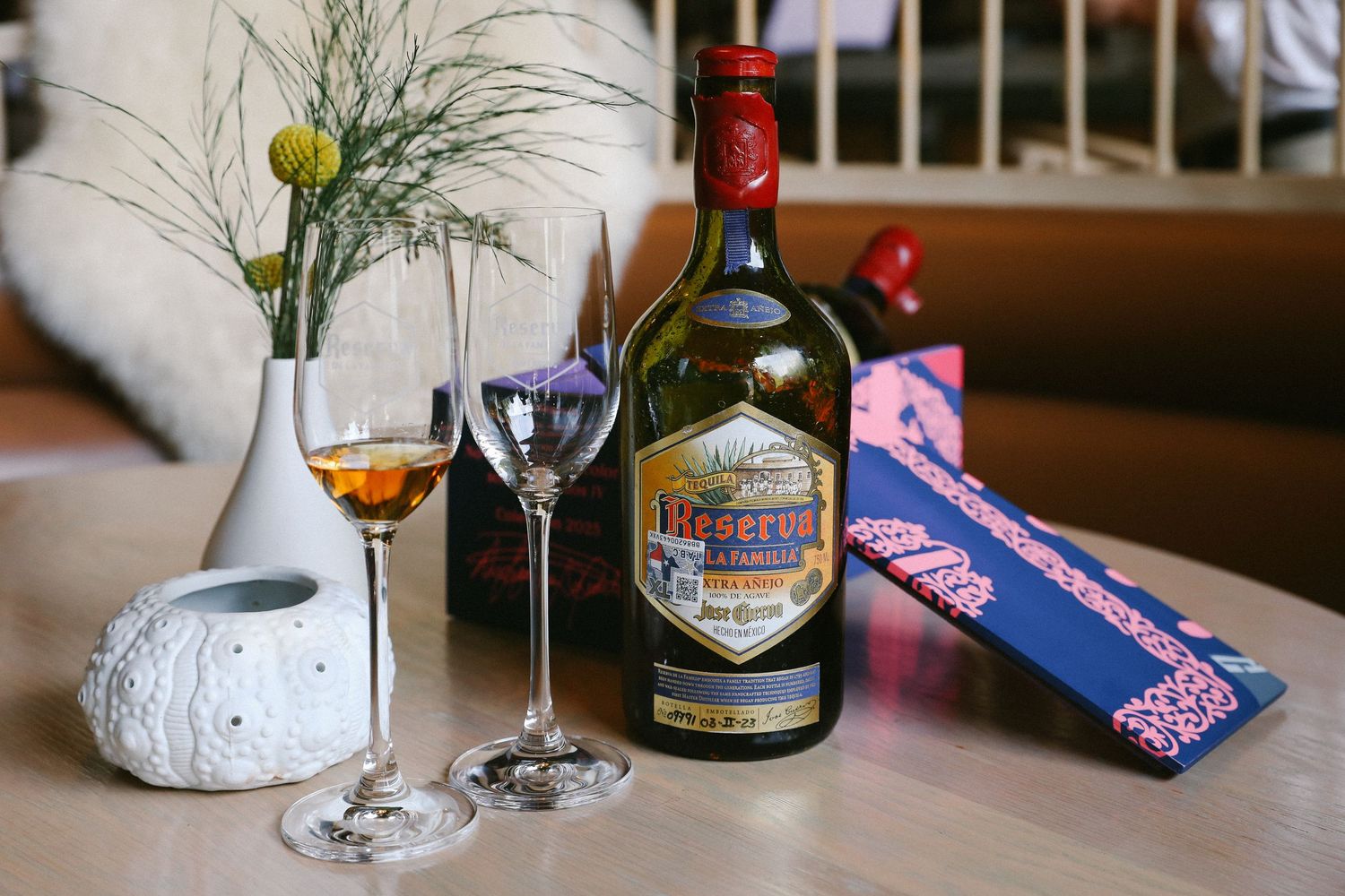 Reserva brandy bottle with two elegant crystal glasses on a wooden table with floral decoration.
