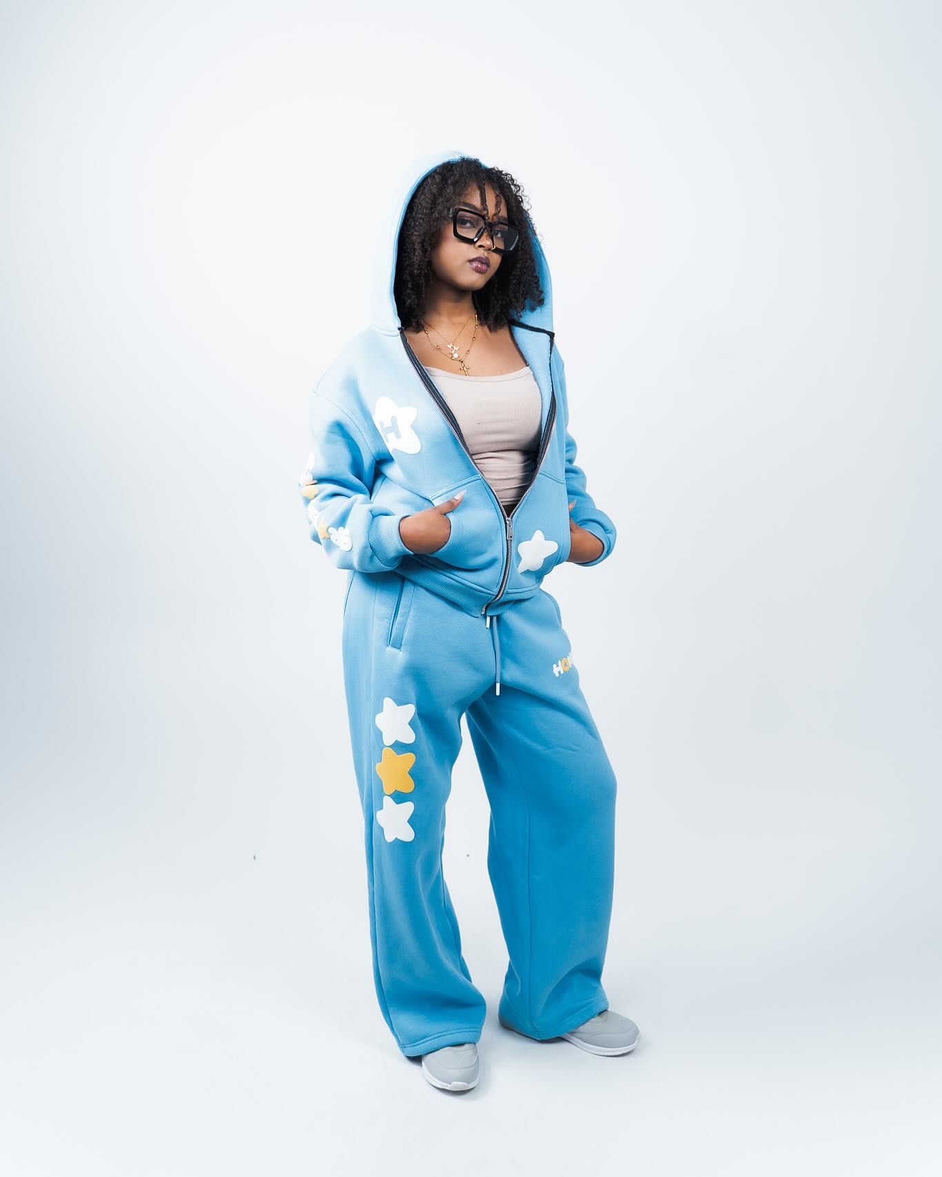 Woman wearing a blue star-print hoodie and wide-leg sweatpants set, posed against a white background.