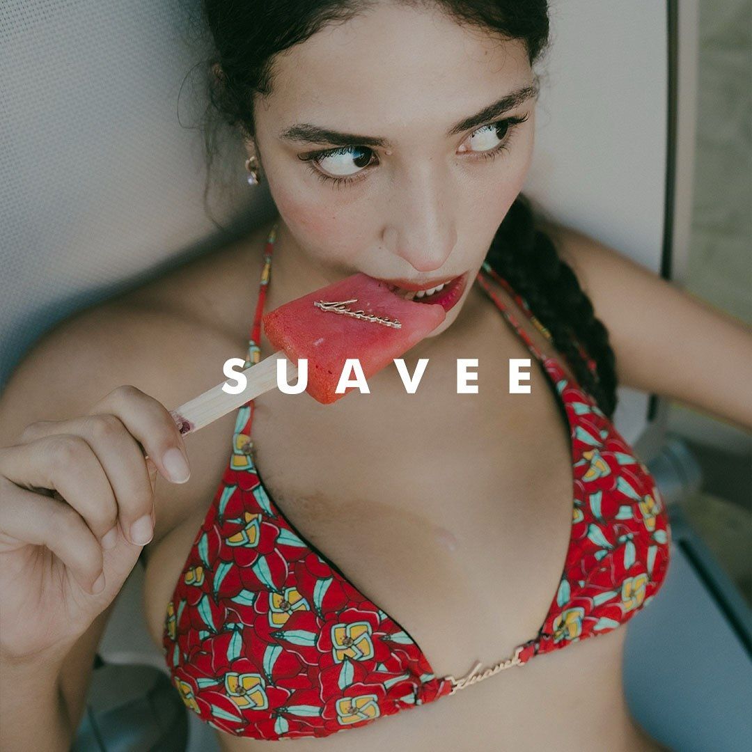Young woman in red floral bikini top eating a red popsicle with SUAVEE text overlay.