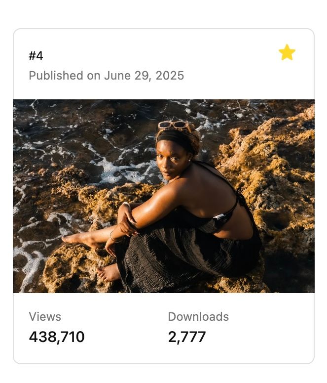 A woman in a black swimsuit sits on rocky coastal cliffs with ocean waves crashing behind her.