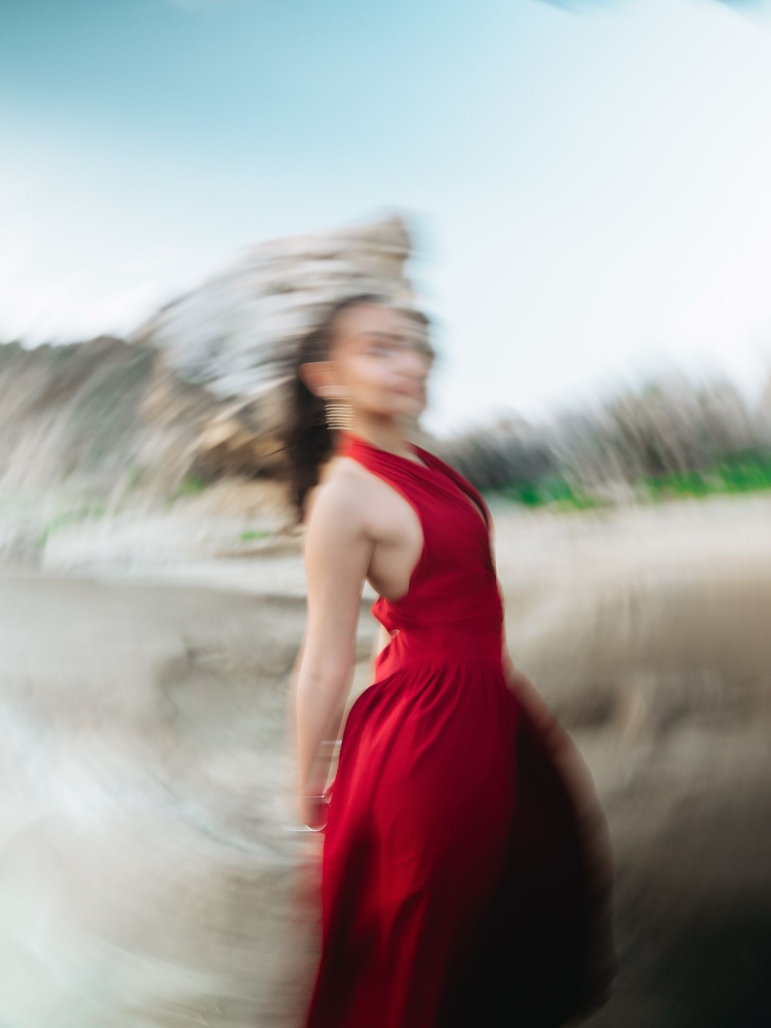 A woman in a flowing red dress spins gracefully outdoors, captured with motion blur effect.
