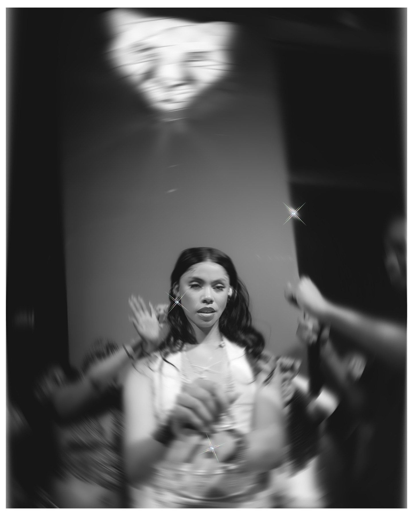 Black and white photo of a young woman at a party, surrounded by blurred motion and soft bokeh lights.