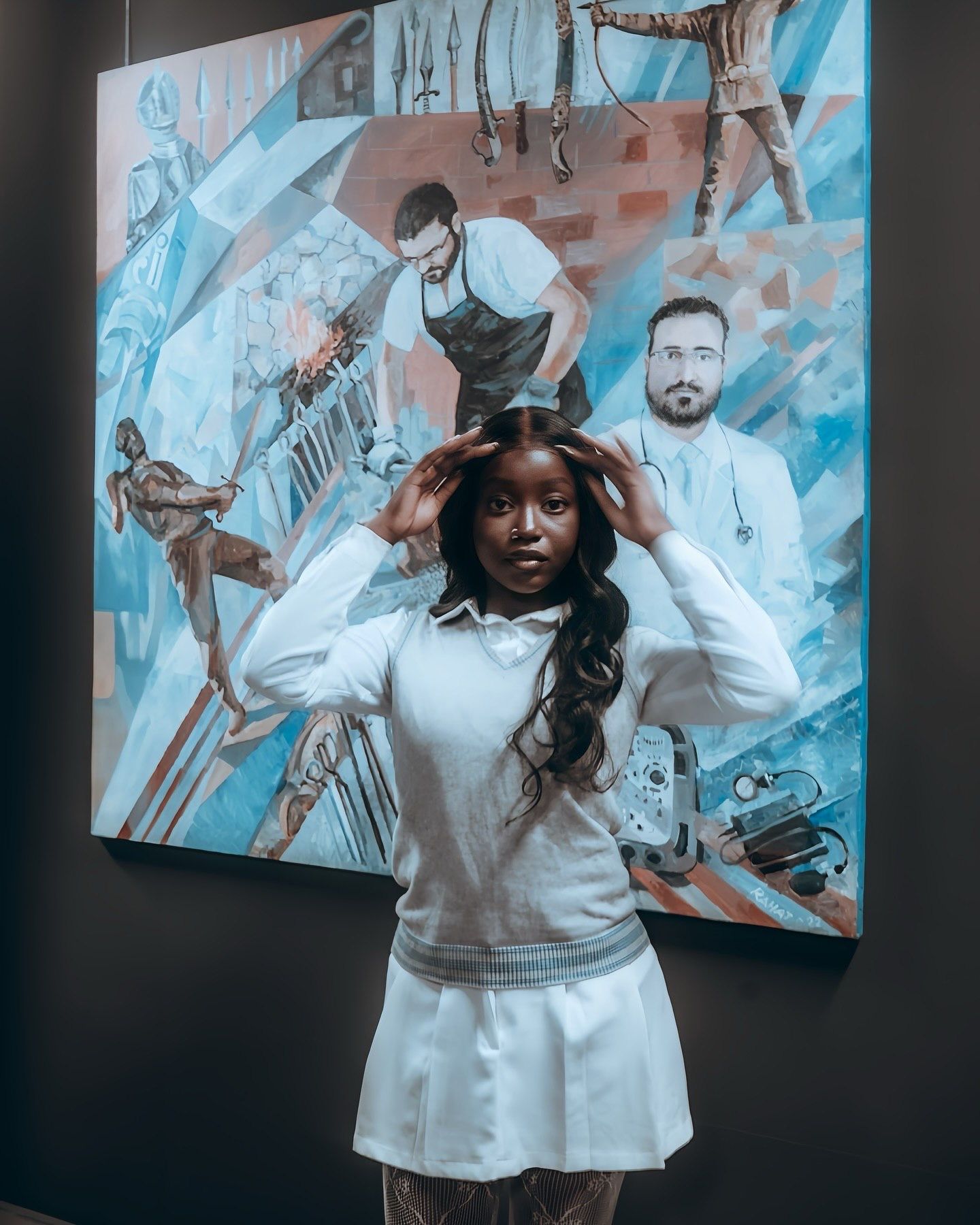 Young woman in white outfit poses in front of a large colorful painting featuring medical professionals in an art gallery.