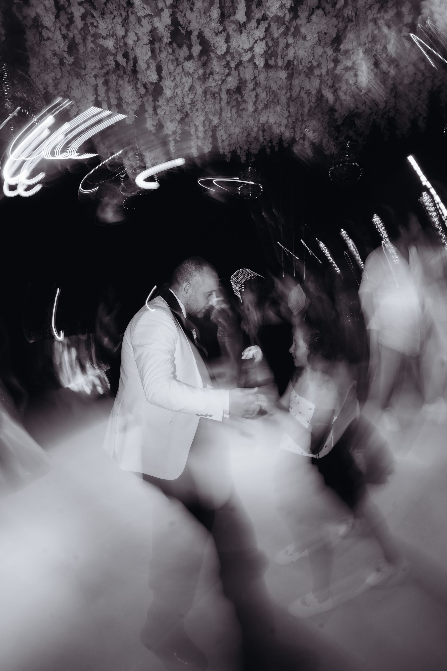 Black and white blurred photo of a couple sharing their first dance at a wedding reception with light trails.