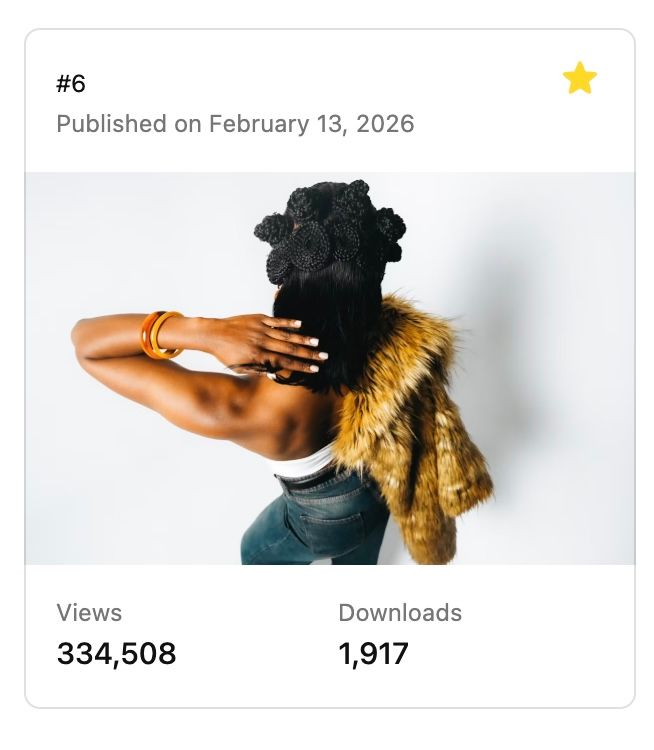 A Black woman poses with her back turned, wearing a fur stole and gold bracelets, with natural hair styled up.