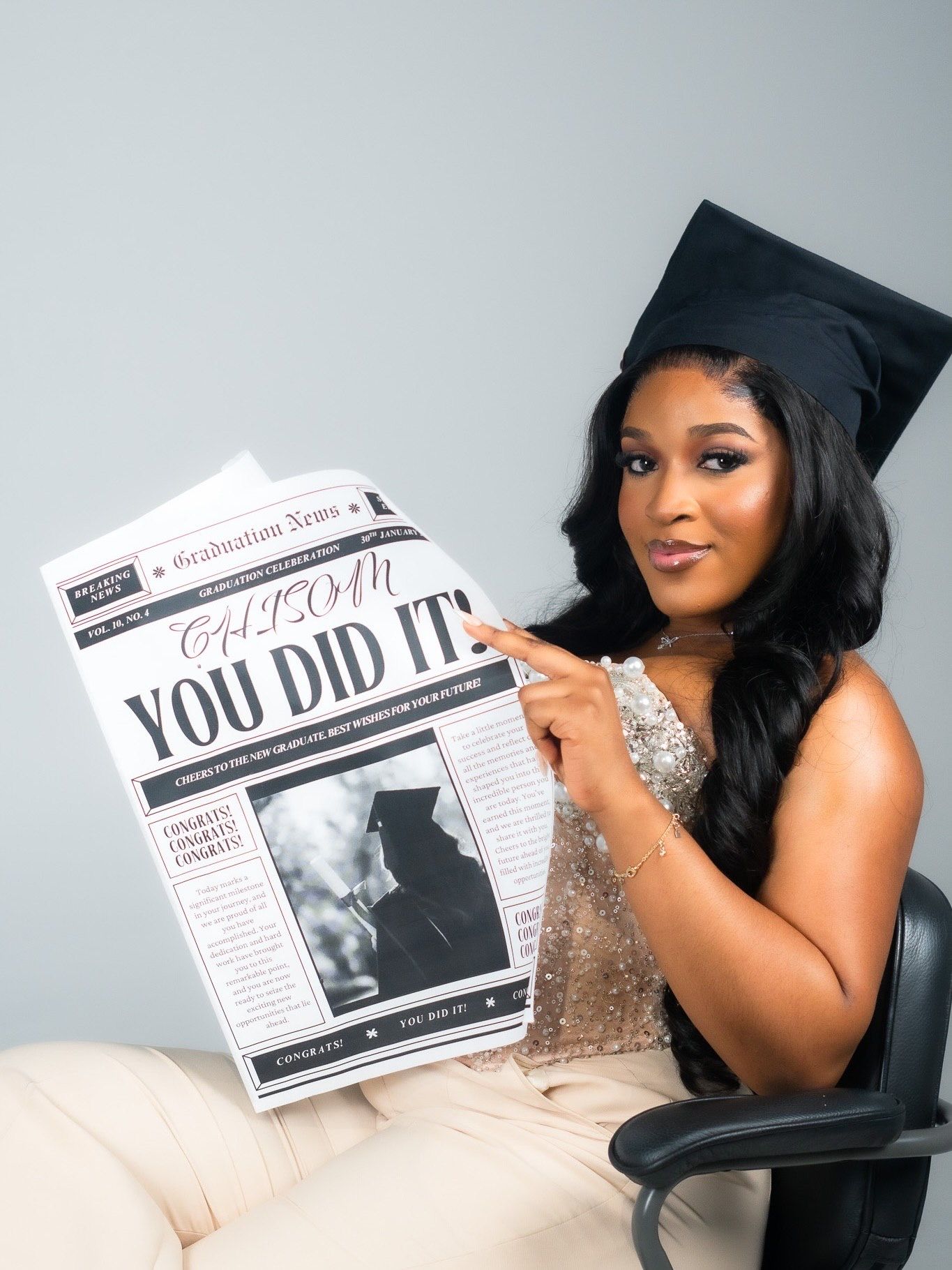 Graduate in cap holding personalized newspaper headline reading YOU DID IT.