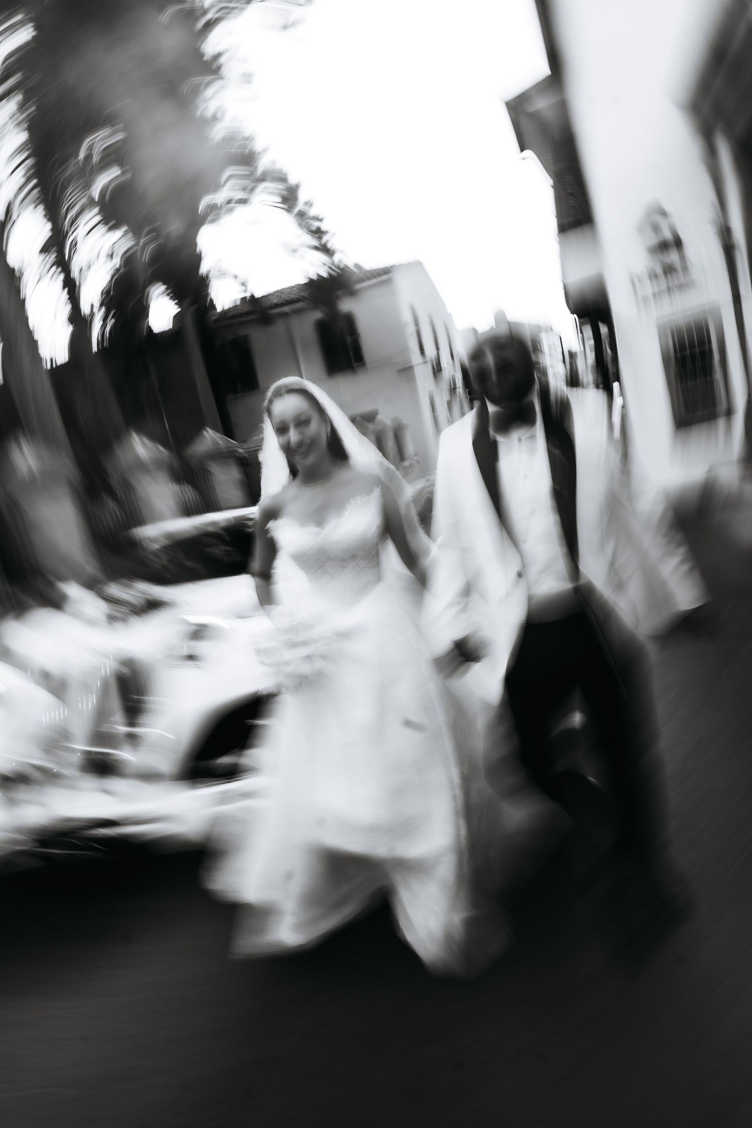 Black and white photo of a bride and groom walking together outdoors after their wedding ceremony.