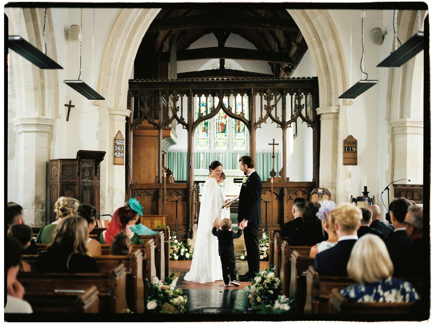 Bride and groom exchange vows at a traditional church wedding ceremony with wooden altar and stained glass windows.