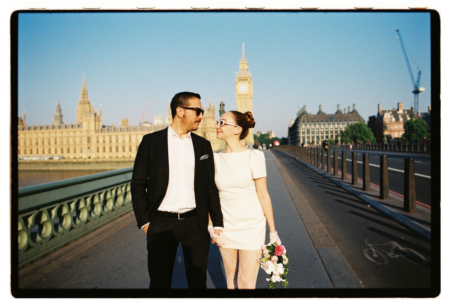 Newlyweds sharing a romantic moment on Westminster Bridge with Big Ben visible behind them.