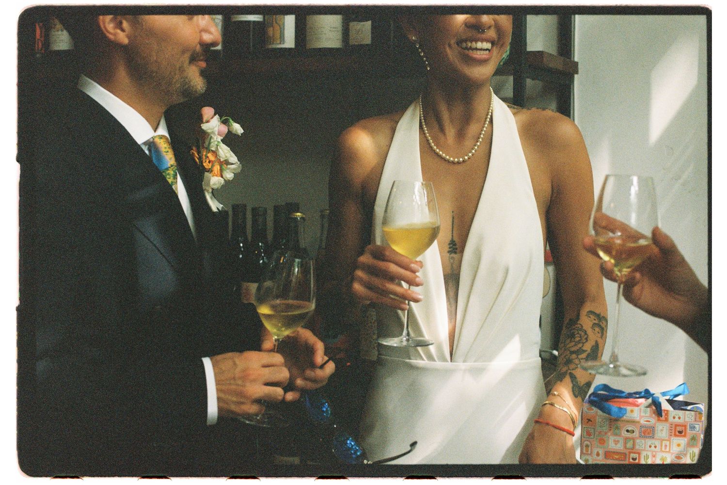 Bride in halter wedding dress toasting with champagne alongside groom at wedding reception.
