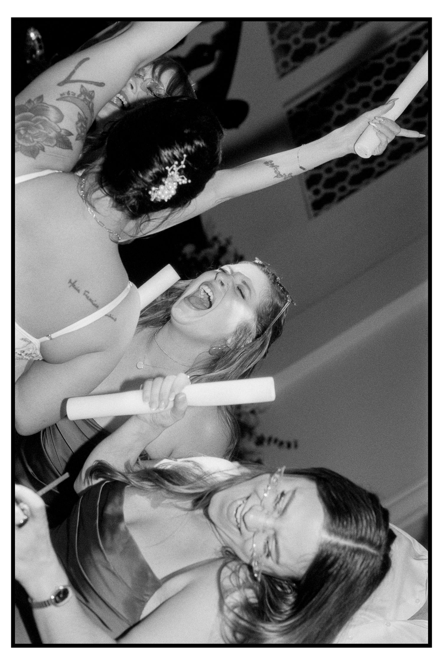 Black and white photo of joyful wedding guests dancing and celebrating at lively reception.