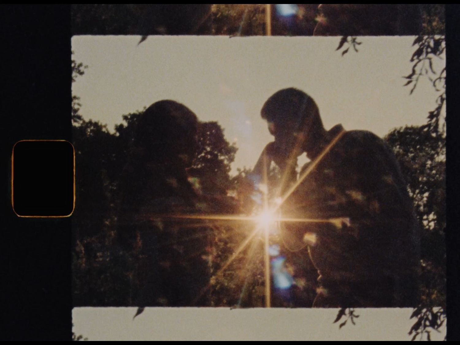 Two silhouetted figures facing each other with a sunburst between them, surrounded by lush green trees.