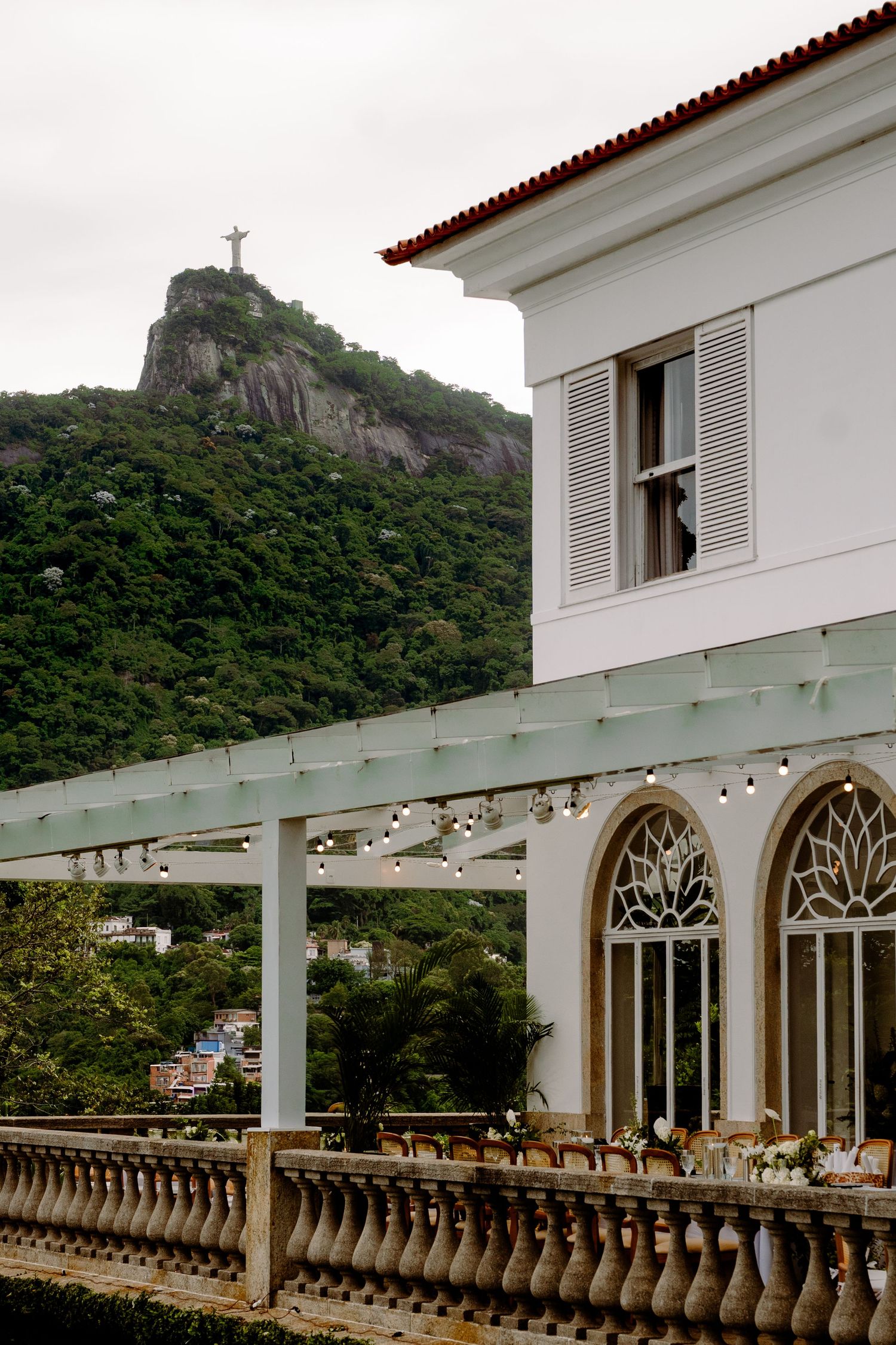 Elegant wedding venue terrace with Christ the Redeemer statue visible on misty mountain.