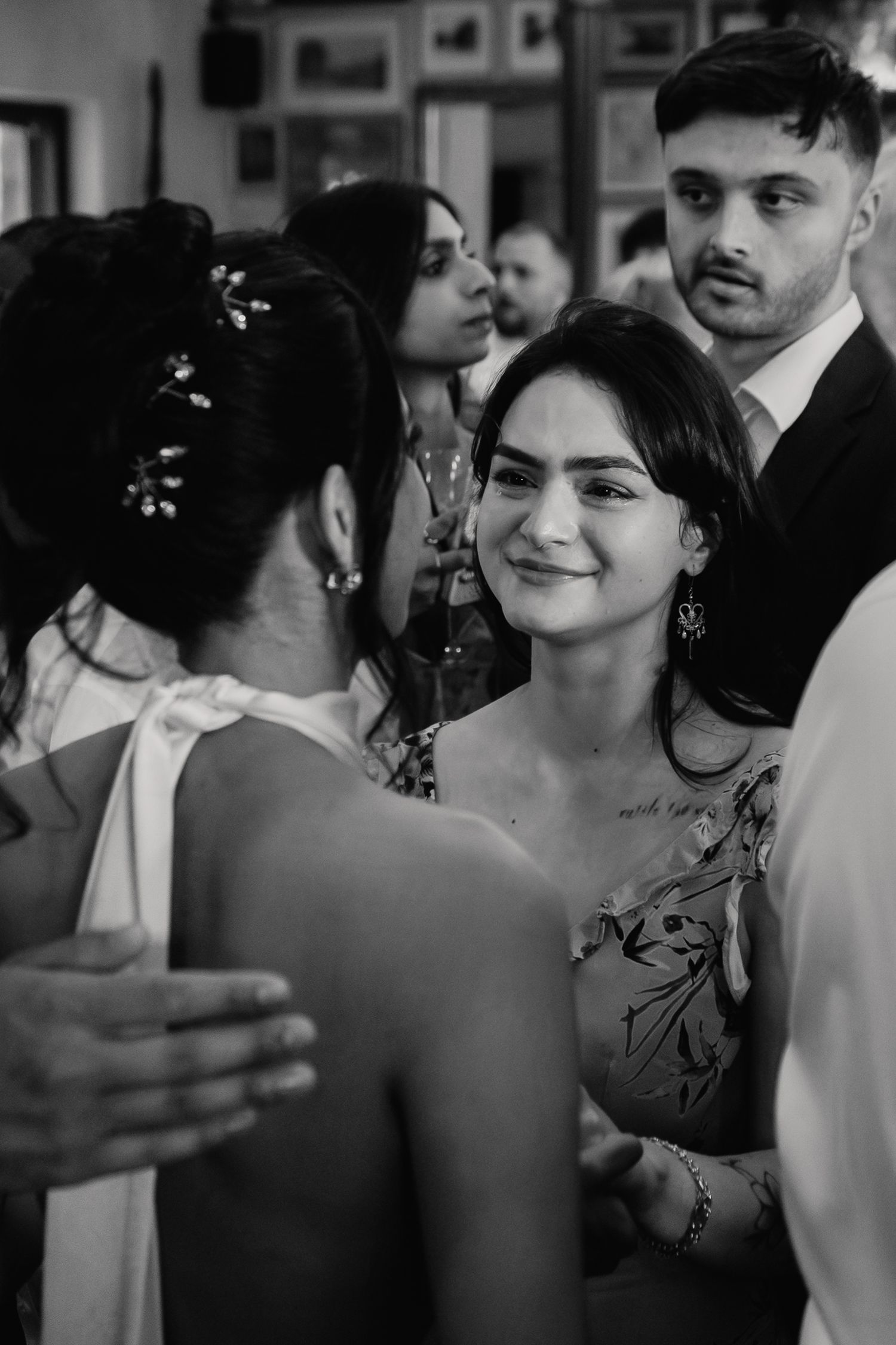 A smiling female wedding guest with floral tattoos chats warmly with the bride at the reception.
