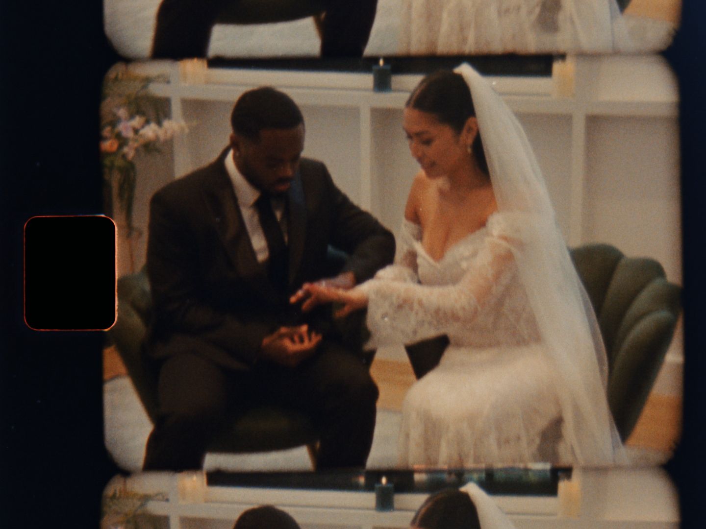 Couple exchanging rings during intimate wedding ceremony seated in decorated venue.
