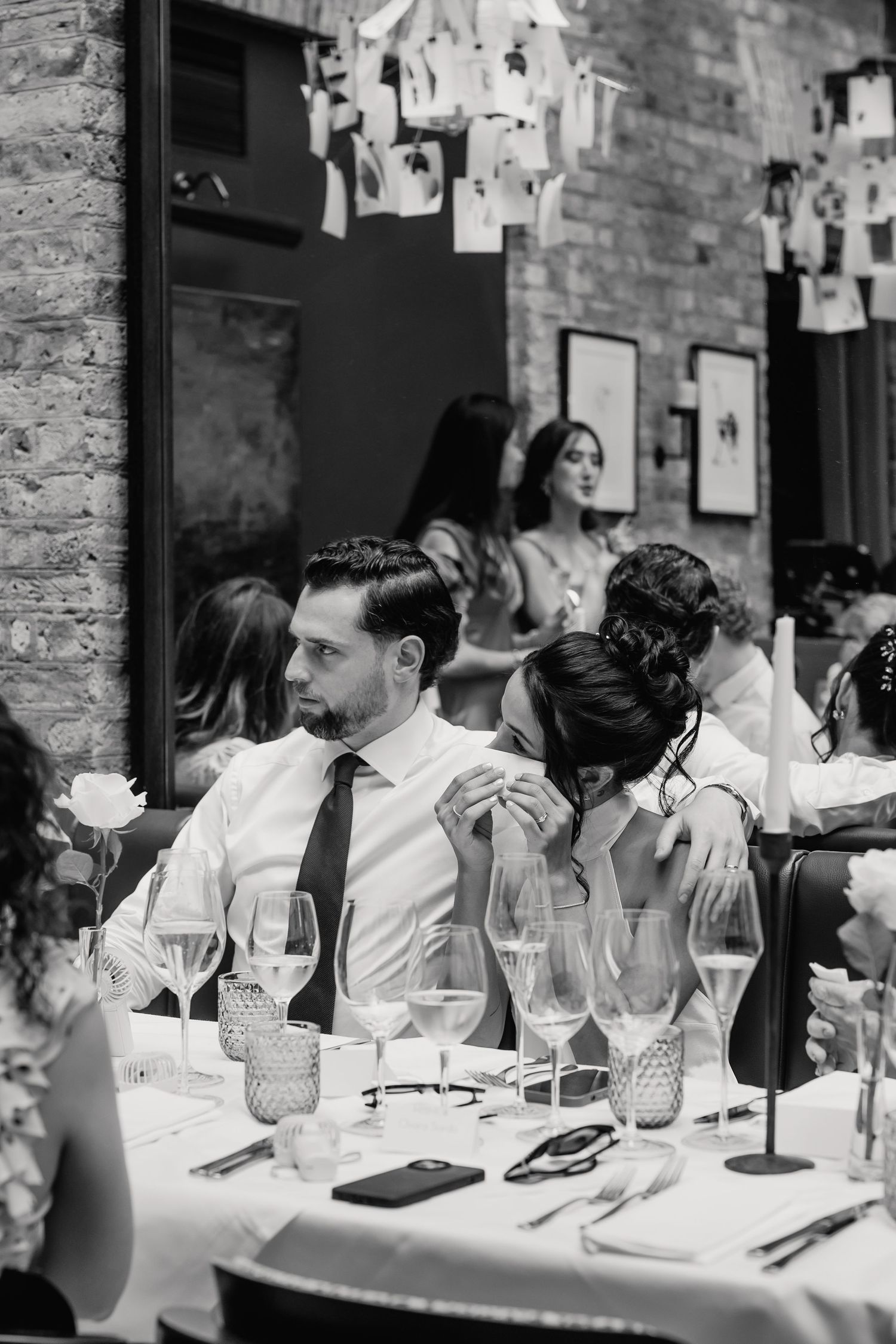 Black and white photo of bride and groom sitting intimately at wedding table.