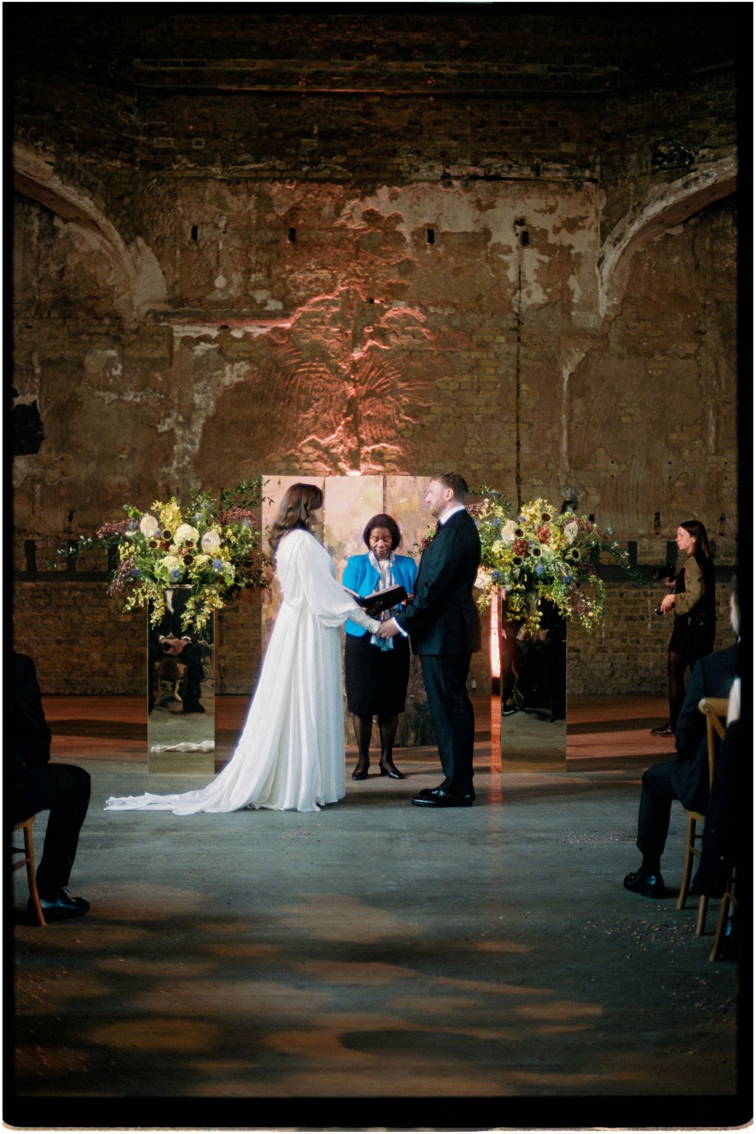 Bride and groom exchange vows at altar in rustic brick ceremony venue.
