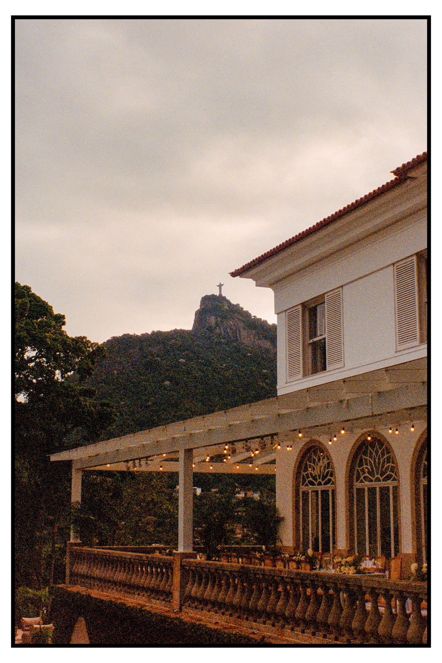Historic white villa wedding venue with string lights and Christ the Redeemer visible on hilltop.