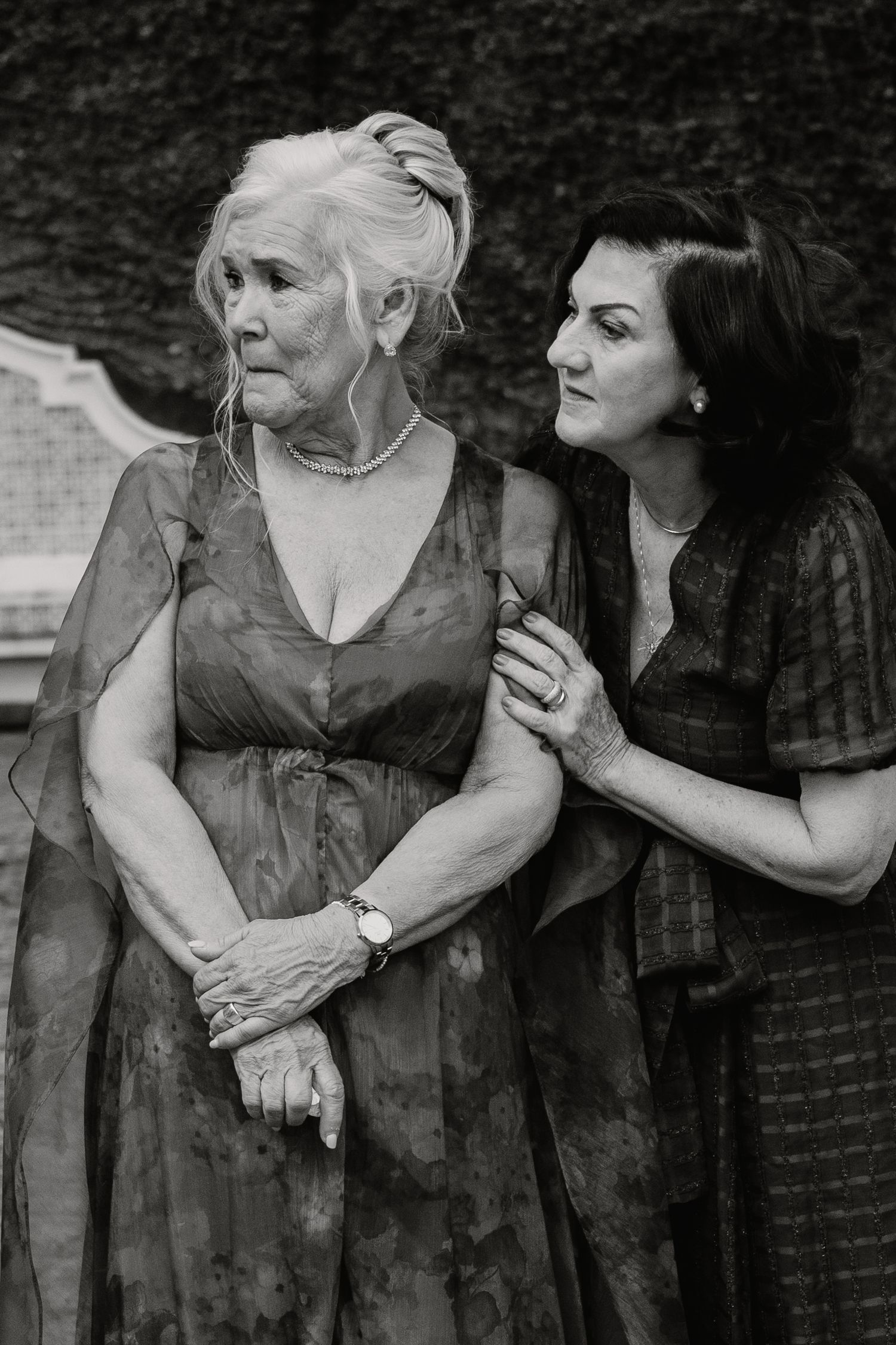 Black and white portrait of elderly woman and younger woman sharing tender moment at wedding.