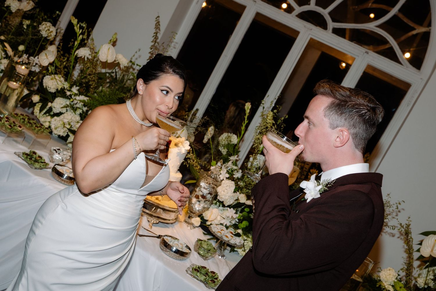 Bride and groom share an intimate champagne toast at elegantly decorated wedding reception table.