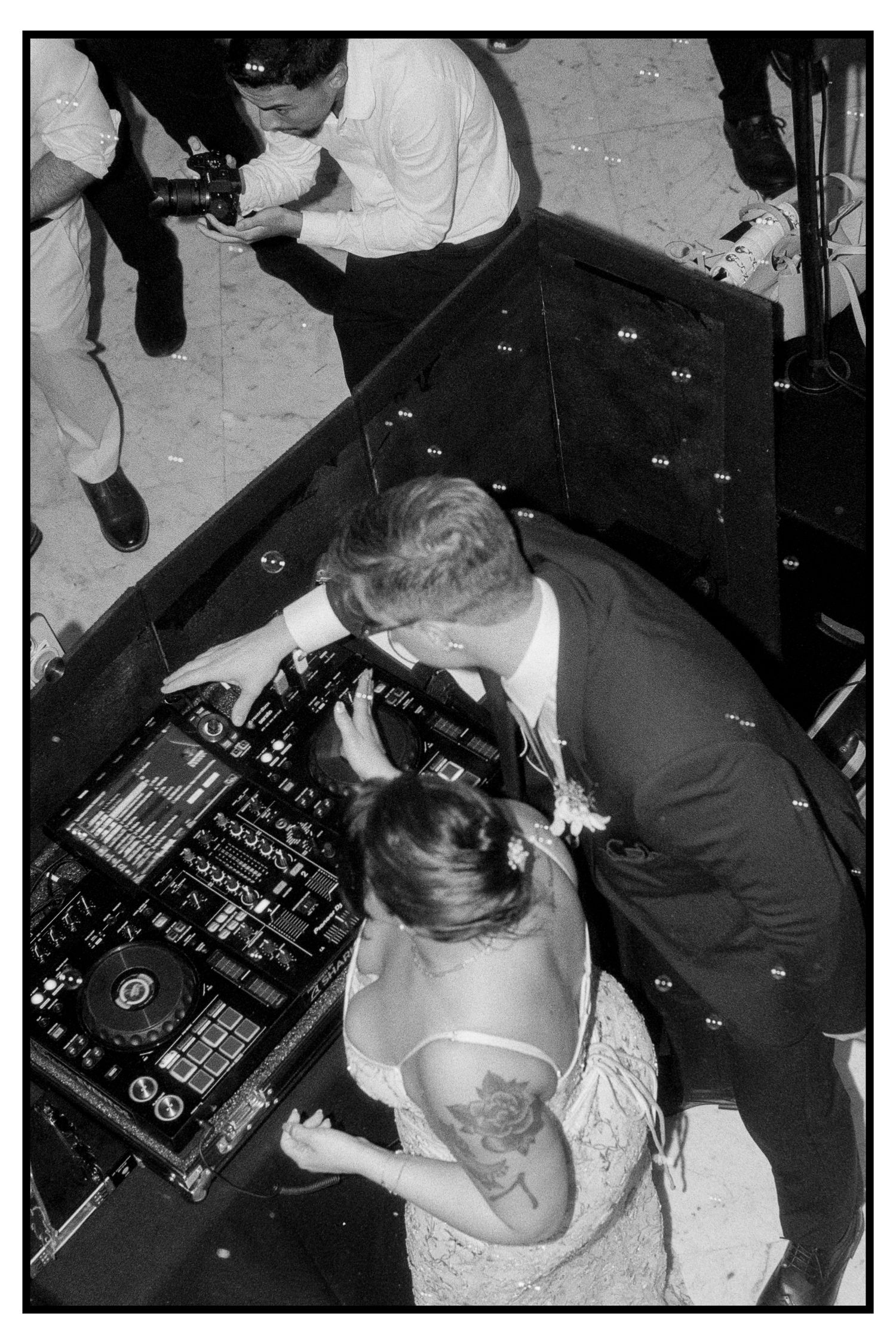 Aerial black and white shot of bride and groom at DJ booth during wedding reception.