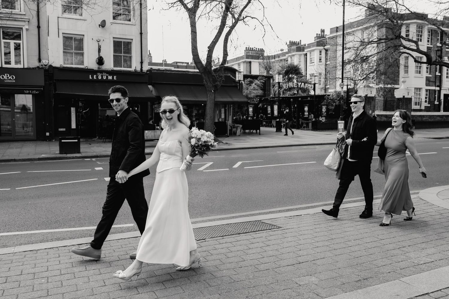Bride and groom crossing a busy London street in black and white wedding photo.