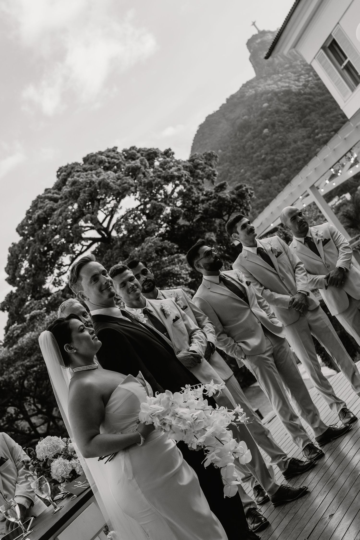 Black and white photo of bride and groom at altar with Christ the Redeemer mountain backdrop.