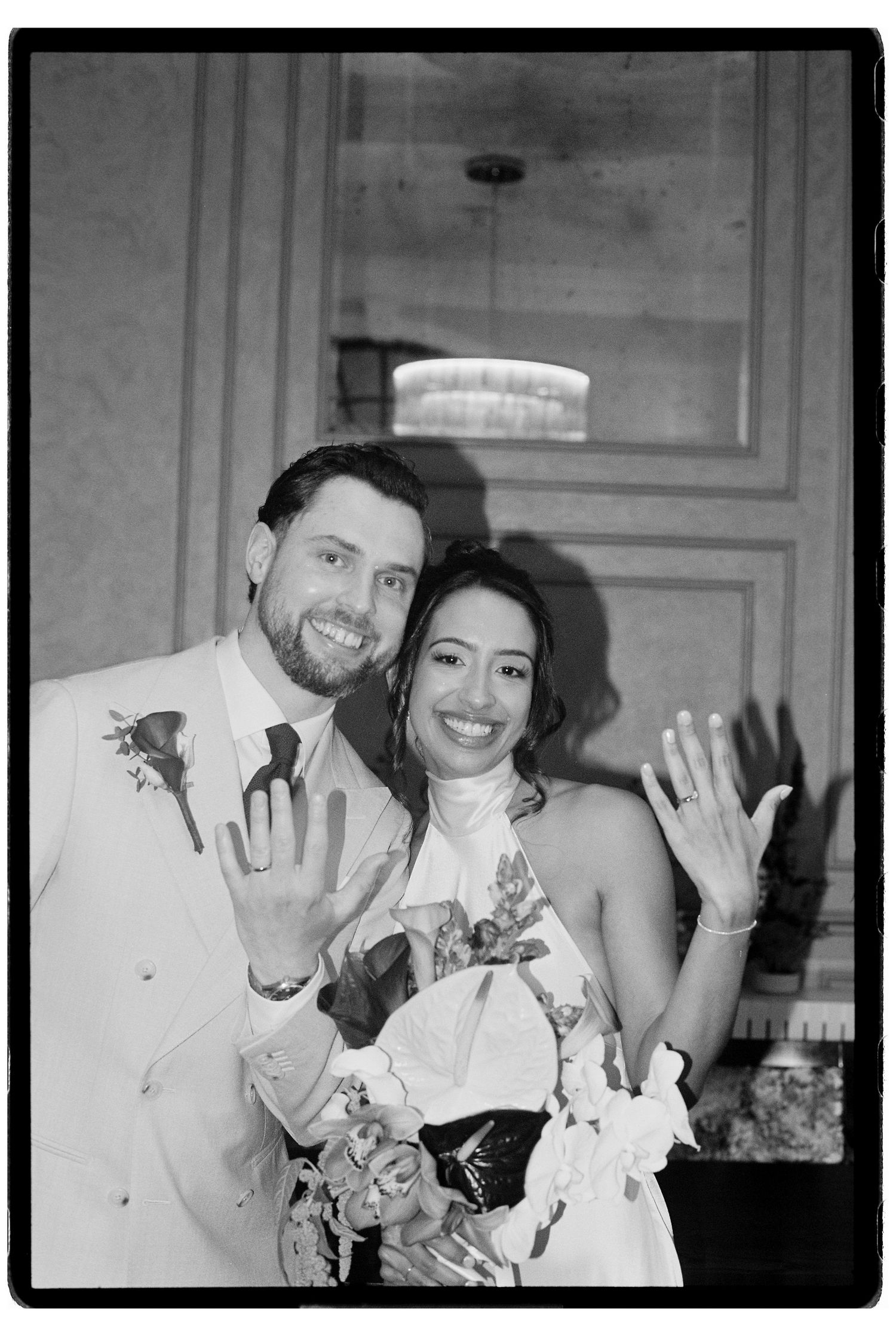 Black and white photo of newlyweds showing off wedding rings after ceremony.