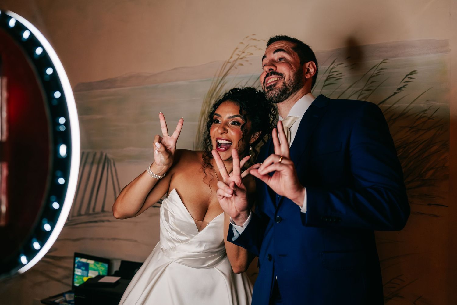 Bride and groom pose playfully making peace signs at their wedding reception photo booth.