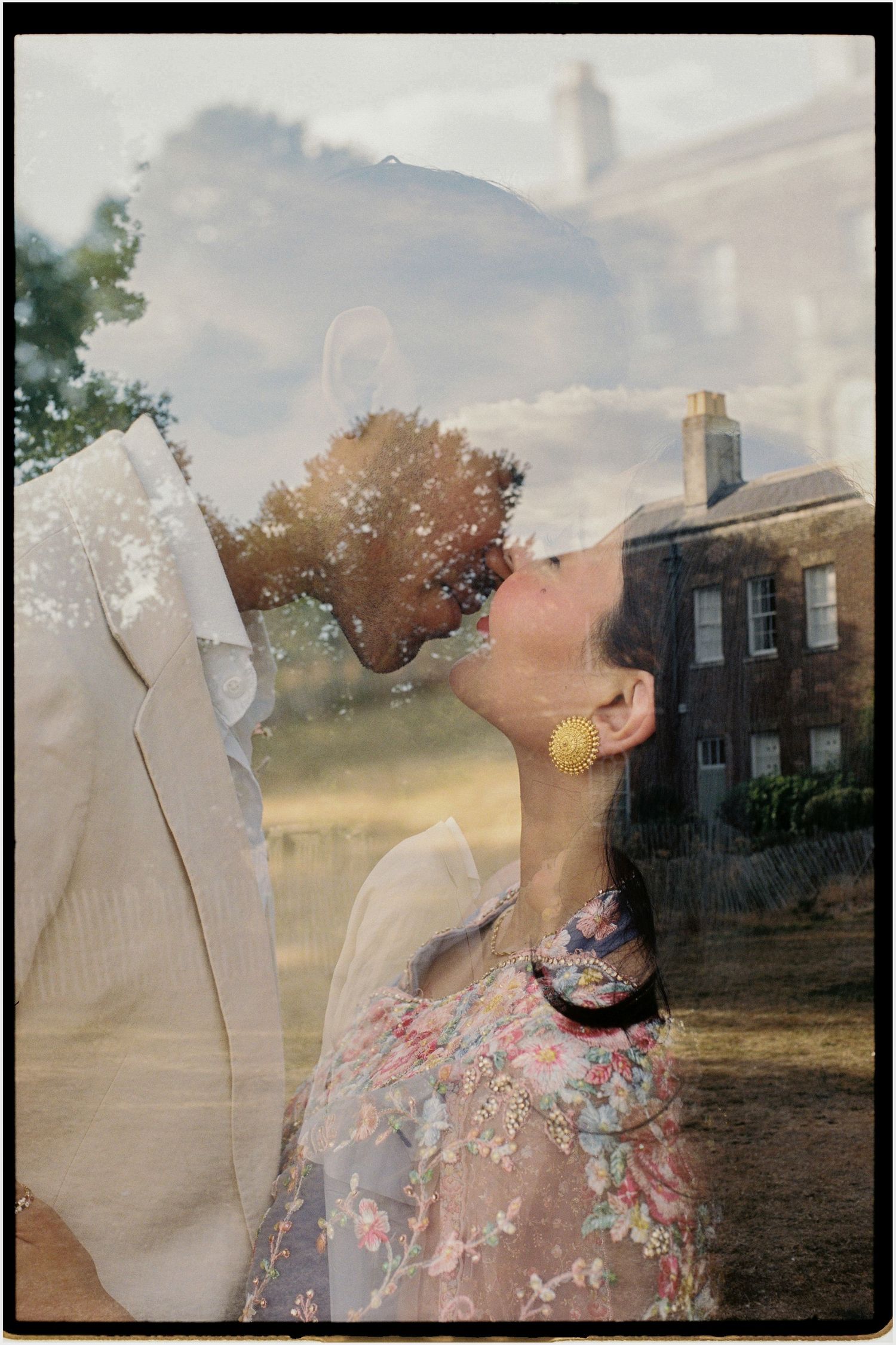 Double exposure film photo of couple kissing overlaid with a floral dress and historic manor house.
