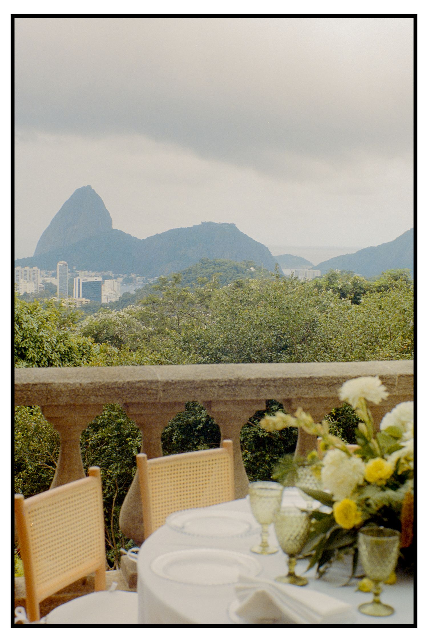 Wedding reception table with yellow flowers and wine glasses overlooking Sugarloaf Mountain in Rio.
