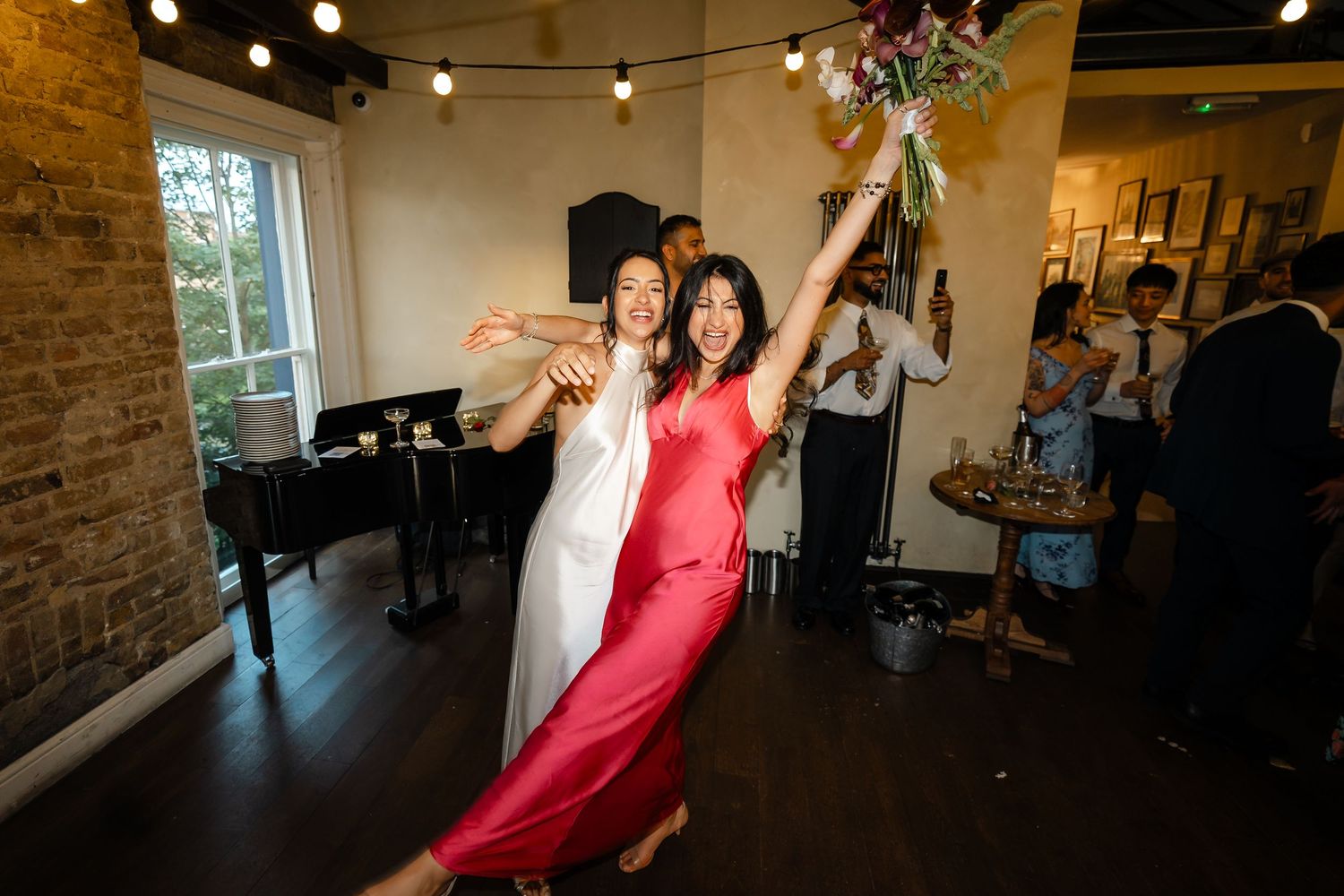 Bride and bouquet catcher celebrating joyfully together on the dance floor at wedding reception.