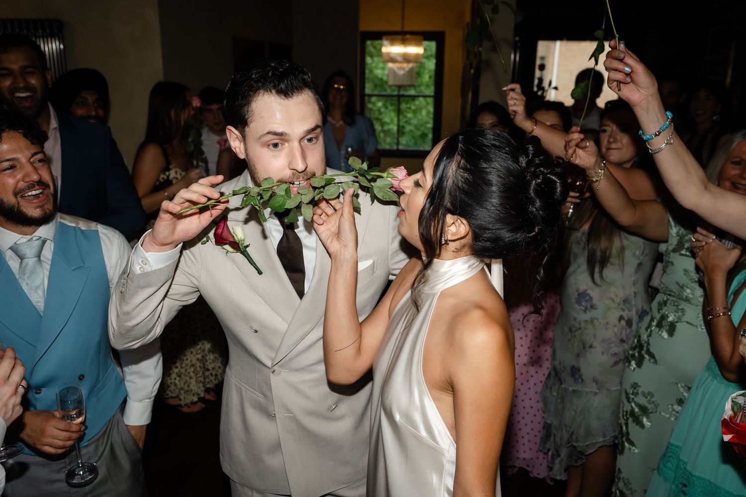 Bride and groom playfully bite into greenery together on the dance floor at their wedding reception.